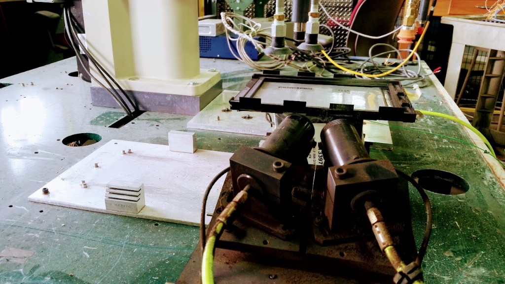 Early prototype workbench with a framed cell assembly, actuators, hoses, and workshop wiring.
