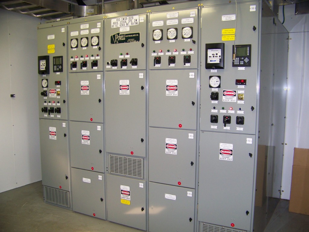 Powell industrial switchgear line-up with analog gauges, controls, and high-voltage warning labeling